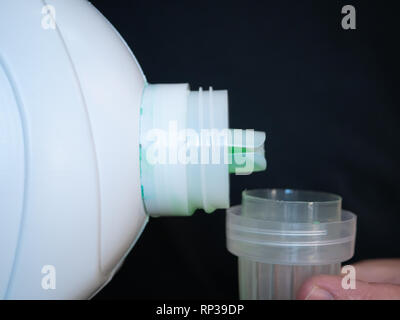 Closeup of liquid gel detergent pouring from the spout of a plastic bottle  into a measuring cup, with dirty washing / laundry in the background Stock  Photo - Alamy