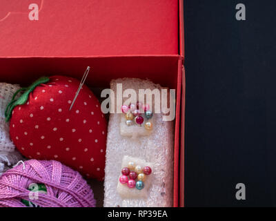 box full of handmade tools for craft sewing. pins, needles, thread on black background Stock Photo