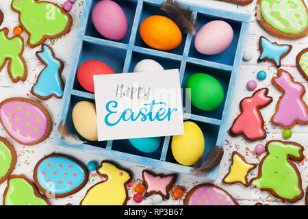 Easter greeting card with colorful gingerbread cookies and easter eggs. Top view on wooden table with space for your greetings Stock Photo