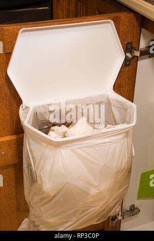 Trash bag on an opened kitchen cabinet door Stock Photo