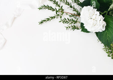Festive wedding, birthday composition with eucalyptus parvifolia branches, hydrangea flowers and silk ribbon. White table background. Rustic styled Stock Photo