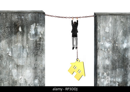 Businessman shackled by gold house hanging on iron chains connected two concrete walls, isolated on gray background. Stock Photo