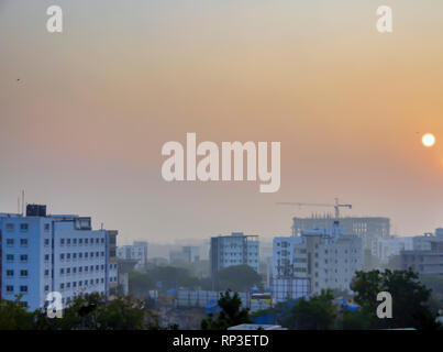 Sun rising in Kondapur and HITEC city, Hyderabad, Telangana, India. The landscape is covered under early morning mist and smog, late January.