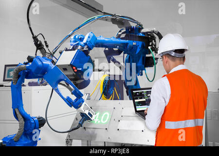 Engineer using laptop computer control laser robotic cutting on metal plate, Industry 4.0 concept Stock Photo