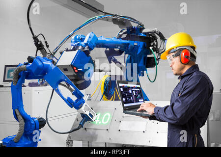 Engineer using labtop computer control laser robotic cutting on metal plate, Industry 4.0 concept Stock Photo