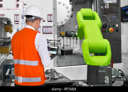 Engineer using laptop computer control automatic robotic hand machine tool with CNC machine in automotive industry, Industry 4.0 concept Stock Photo