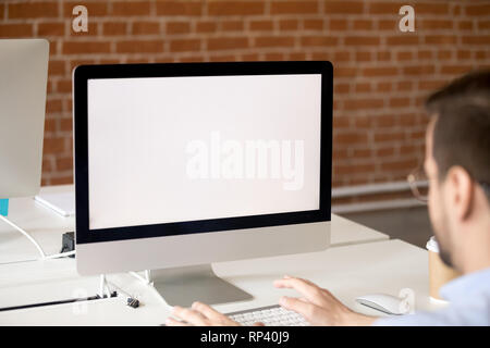 Businessman sitting at desk in office working using laptop with white mockup blank screen close up view over shoulder. Worker chatting typing email me Stock Photo