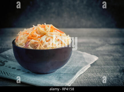 In a ceramic Cup on an old wooden table sauerkraut with carrots. Stock Photo