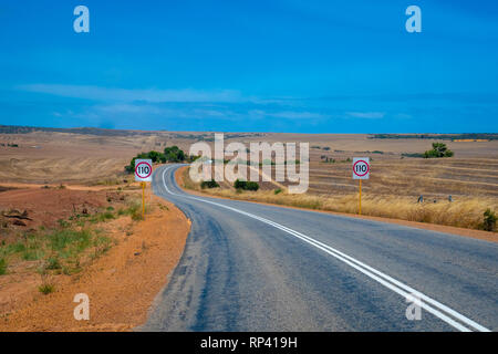 Australian bush road leading through dry landscape and farmland with speed limit 110 kph Stock Photo