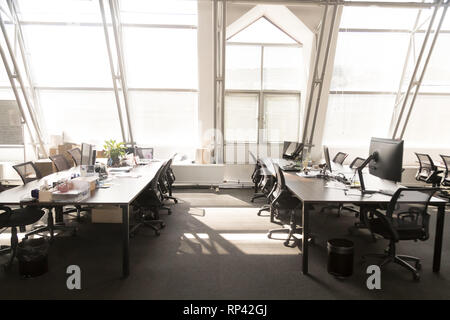 Modern light spacious office room interior. Computers on tables black chairs on wheels, sunlight through the panoramic windows. Comfortable contempora Stock Photo