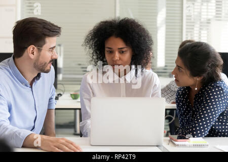 Black african team leader shares idea and information with caucasian and indian coworkers. Diverse multiracial workers working on project together sit Stock Photo