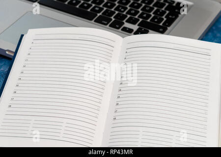 Opened clean business notebook and laptop. Business notebook for record important events and meetings with business partners on the marble table Stock Photo