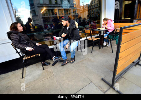 London, England, UK. Young couple drinking coffee and talking outside a cafe Stock Photo
