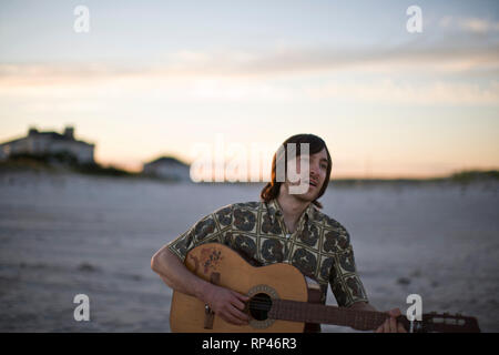 Young man playing a guitar on a beach. Stock Photo