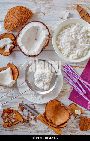 ingredients for coconut cocktail of coconut water, coconut milk and cream on a white wooden table, vertical view from above Stock Photo