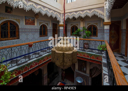 Inner courtyard with tiled walls and floor from mosaic. Traditional ornate and colorful arabesque wall carvings above an archway in Moroccan riad Stock Photo