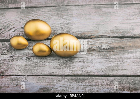 Background of Golden eggs on a wooden surface Stock Photo