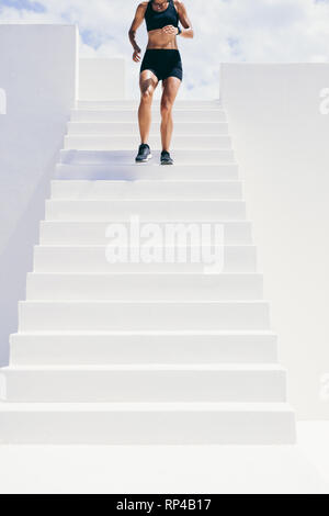 Cropped shot of a woman in fitness wear running downstairs. fitness woman doing workout running down the stairs of a building. Stock Photo