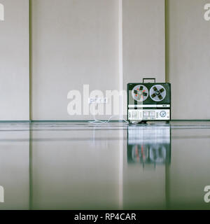 vintage analog magnet tape recorder standing on the floor near wall. Stock Photo