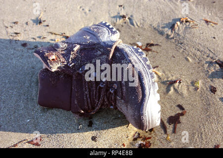 work boot. object of clothing abandoned among the dirt on a sandy beach Stock Photo