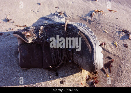 work boot. object of clothing abandoned among the dirt on a sandy beach Stock Photo