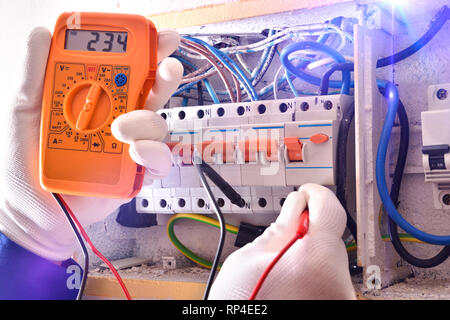 Electrical installer with protective elements making electrical measurements in an electrical box with a tester Stock Photo