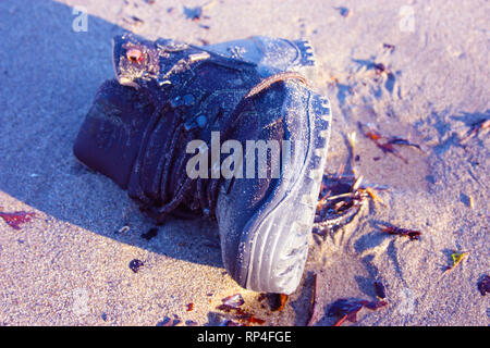 work boot. object of clothing abandoned among the dirt on a sandy beach Stock Photo