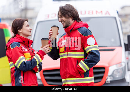 Smiling paramedics drinking coffee in front of ambulance car Stock Photo