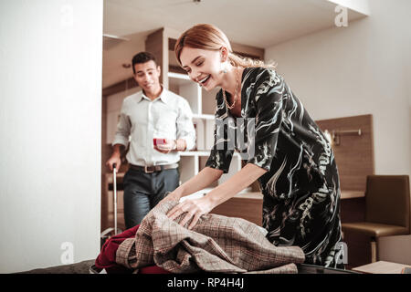 Wife laughing while packing her luggage having business trip with her man Stock Photo