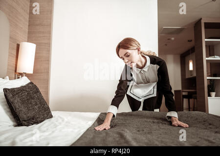 Hard-working young housekeeper making the bed in the morning Stock Photo