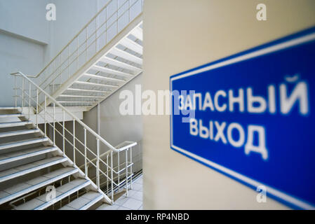 Moscow, Russia - 5 April, 2018: Emergency exit sign in Russian and multi-flight stairway in modern house. Stock Photo