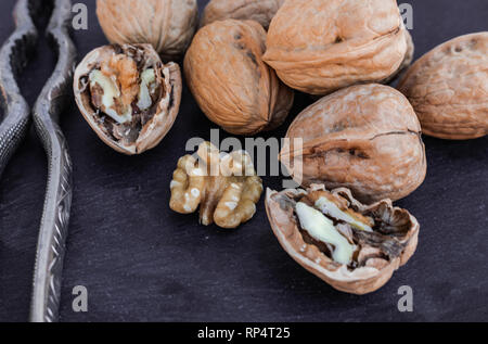Walnuts and nutcracker on black surface Stock Photo
