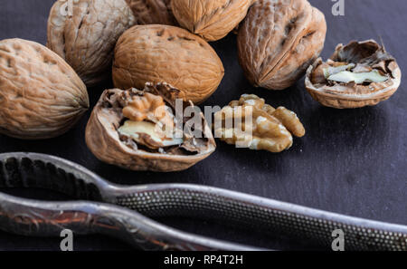 Walnuts and nutcracker on black surface Stock Photo