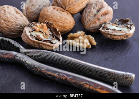 Walnuts and nutcracker on black surface Stock Photo