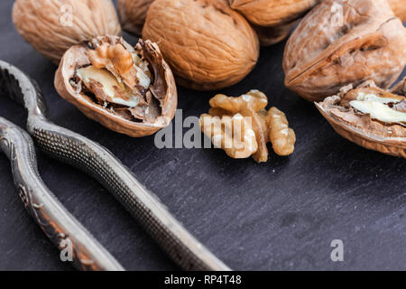 Walnuts and nutcracker on black surface Stock Photo