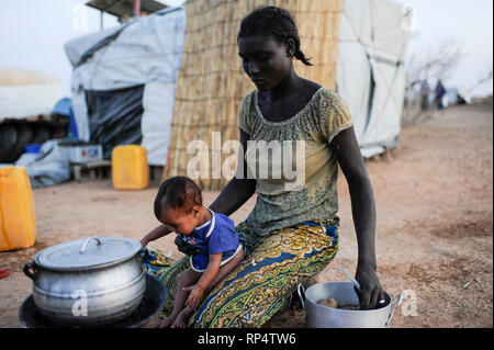 BURKINA FASO Djibo, malian refugees, mostly Touaregs, in refugee camp Mentao of UNHCR, they fled due to war and islamist terror in Northern Mali, black african housemaid and babysitter of Tuareg family cooking stove Stock Photo