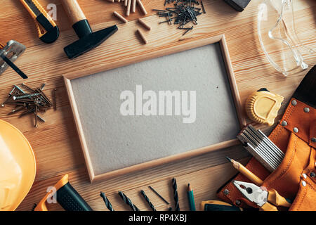 Empty picture frame as copy space mockup on carpentry woodwork desk among various tools of trade Stock Photo