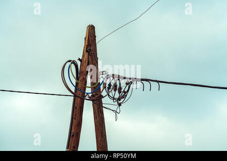 Wooden electricity pylon with wires against the blue sky Stock Photo