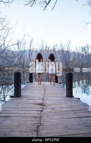 Teenage twin sisters holding hands on white background Stock Photo - Alamy