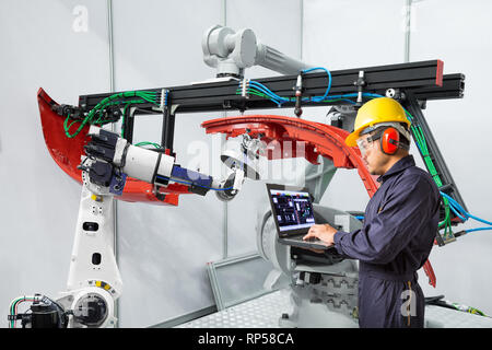 Engineer using laptop computer maintenance robot grip automotive workpiece, Smart factory concept Stock Photo