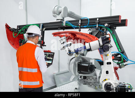 Engineer using laptop computer maintenance robot grip automotive workpiece, Smart factory concept Stock Photo