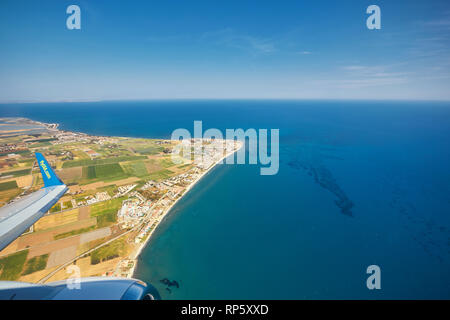 The plane is flying over the island of Cyprus. Airplane wing in flight from window. Stock Photo