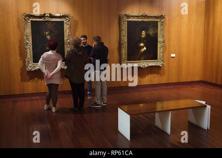 Visitors in front of the paintings 'Pallas Athena' and 'Portrait of an Old Man' by Rembrandt displayed in the Calouste Gulbenkian Museum (Museu Calouste Gulbenkian) in Lisbon, Portugal. Both paintings were sold by the Bolsheviks from the collection of the Hermitage Museum (then Leningrad, USSR, now Saint Petersburg, Russia) to British businessman and philanthropist Calouste Gulbenkian in 1930. Stock Photo