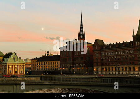 Moon rising over Gamla Stan and behind Riddarholmskyrkan in front of red sunset sky during summer (Stockholm, Sweden, Europe) Stock Photo