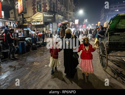 Typical atmospheric busy noisy night time street scene in Kolkata with local people, rickshaws and street food vendors. Stock Photo