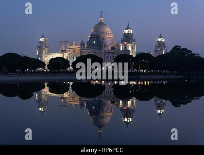 A night time dusk evening view of the Queen Victoria memorial in Kolkata reflected mirrored in the water of the western pond. Stock Photo