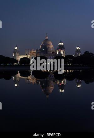 A night time dusk evening view of the Queen Victoria memorial in Kolkata reflected mirrored in the water of the western pond. Stock Photo