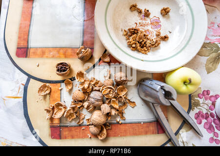 Flat top view walnut nut unshelled brown color shells pile of group of many on placemat table with apple tool Stock Photo