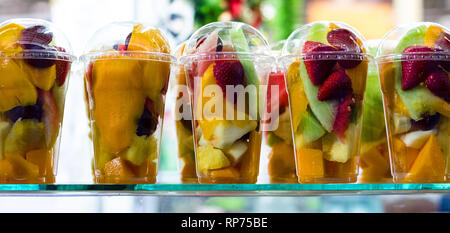 Fruit salad in plastic cups takeaway. Sliced organic fruits and berries, healthy snack to go, copy space. Stock Photo