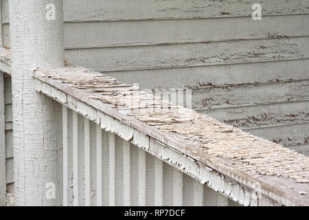 Detail of weathered white paint on a porch railing and wall Stock Photo
